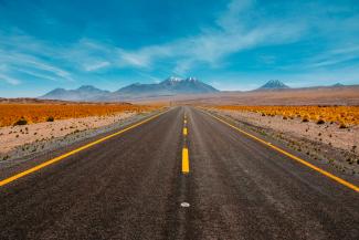 lone road going to mountains by Diego Jimenez courtesy of Unsplash.